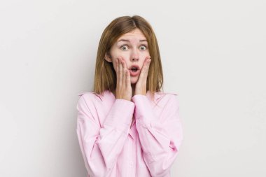 Kızıl saçlı güzel kadın şok olmuş ve korkmuş hissediyor, ağzı açık ve elleri yanaklarında korkmuş görünüyor.