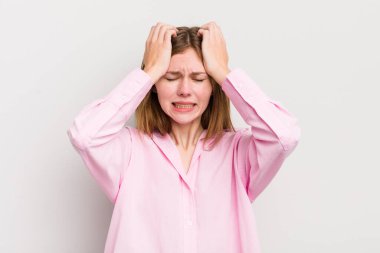 Kızıl saçlı güzel bir kadın stresli ve endişeli, depresif ve hayal kırıklığına uğramış, iki elini de kafa kafaya kaldırıyor.