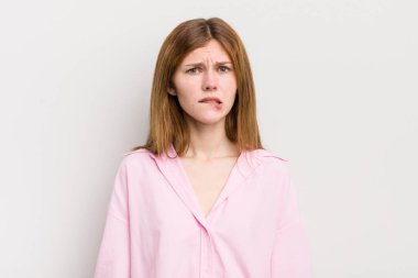 Kızıl saçlı güzel bir kadın kafası karışmış ve kafası karışmış görünüyor. Sinirli bir hareketle dudağını ısırıyor. Sorunun cevabını bilmiyor.