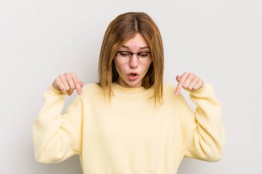 Kızıl saçlı, güzel bir kadın şaşkın, ağzı açık ve şaşkın bakıyor ve şaşkınlıkla onu işaret ediyor.