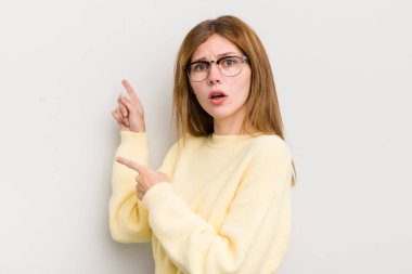 Kızıl saçlı, güzel bir kadın şaşkın ve şaşırmış hissediyor. Yandaki fotokopi alanını işaret ediyor. Şaşırmış ve ağzı açık bakıyor.