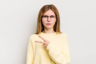 Kızıl saçlı güzel bir kadın mutlu, pozitif ve başarılı hissediyor, göğsünde el yapımı V ile zafer ya da huzur gösteriyor.