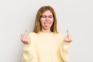 Kızıl saçlı, güzel bir kadın kışkırtıcı, agresif ve müstehcen, isyankar bir tavırla orta parmağını sallıyor.