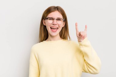 Kızıl saçlı güzel bir kadın mutlu, eğlenceli, kendinden emin, pozitif ve asi, elle rock veya heavy metal işareti yapıyor.