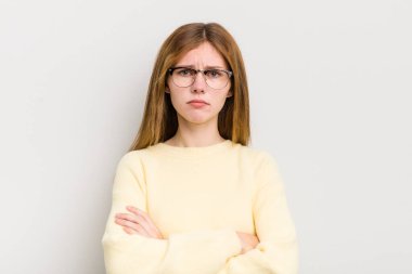 Kızıl saçlı güzel bir kadın hayal kırıklığına uğramış, hayal kırıklığına uğramış, ciddi görünüyor, kızgın ve kollarını kavuşturmuş.