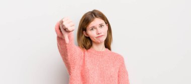 Kızıl saçlı güzel bir kadın kızgın, sinirli, hayal kırıklığına uğramış ya da hoşnutsuz, ciddi bir bakışla başparmaklarını göstermiyor.