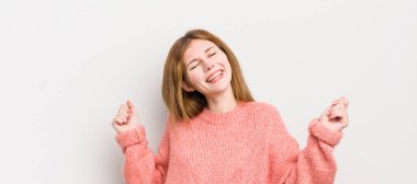 kızıl saçlı güzel kadın gülümsüyor, kaygısız hissediyor, rahat ve mutlu, dans ediyor ve müzik dinliyor, bir partide eğleniyor.