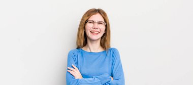 Kızıl saçlı güzel bir kadın mutlu, gururlu ve tatmin olmuş görünüyor. Kollarını kavuşturup gülümsüyor.