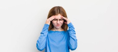 Kızıl saçlı güzel bir kadın stresli ve hayal kırıklığına uğramış görünüyor, baskı altında çalışıyor ve başı ağrıyor.