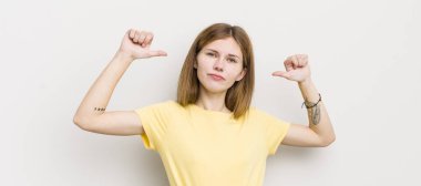 Kızıl saçlı güzel bir kadın gururlu, kibirli ve kendinden emin, tatmin olmuş ve başarılı görünüyor, kendini işaret ediyor.