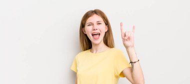 Kızıl saçlı güzel bir kadın mutlu, eğlenceli, kendinden emin, pozitif ve asi, elle rock veya heavy metal işareti yapıyor.