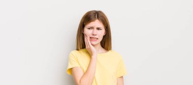 Kızıl saçlı güzel bir kadın, yanağını tutuyor ve acı veren diş ağrısı çekiyor, hasta, mutsuz ve mutsuz hissediyor, dişçi arıyor.