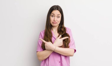 pretty caucasian woman looking puzzled and confused, insecure and pointing in opposite directions with doubts