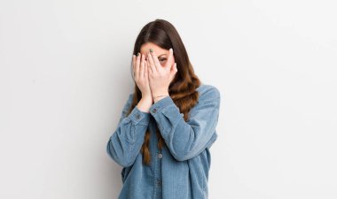 pretty caucasian woman feeling scared or embarrassed, peeking or spying with eyes half-covered with hands
