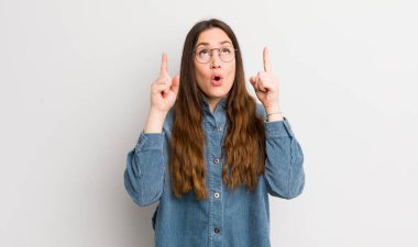 pretty caucasian woman feeling awed and open mouthed pointing upwards with a shocked and surprised look