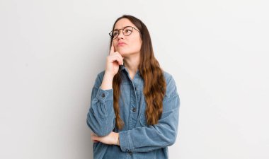 pretty caucasian woman with a concentrated look, wondering with a doubtful expression, looking up and to the side