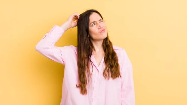 Kafası karışmış, kafası karışmış, kaşınan ve yan tarafa bakan beyaz bir kadın.