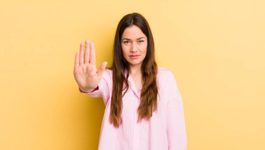 pretty caucasian woman looking serious, stern, displeased and angry showing open palm making stop gesture