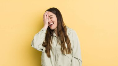 pretty caucasian woman laughing and slapping forehead like saying doh! I forgot or that was a stupid mistake 