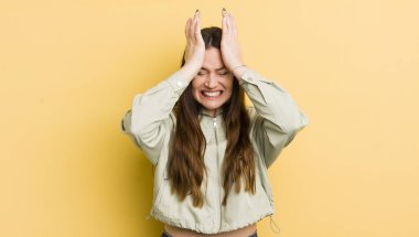 pretty caucasian woman feeling stressed and anxious, depressed and frustrated with a headache, raising both hands to head