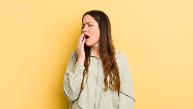 pretty caucasian woman yawning lazily early in the morning, waking and looking sleepy, tired and bored