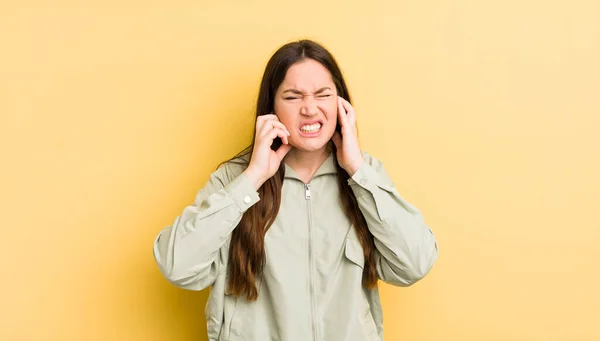 かなり原因のあるアジア系の女性は怒り ストレス いらいらして耳の両方を耳の聞こえない音や音や大きな音楽に覆い — ストック写真