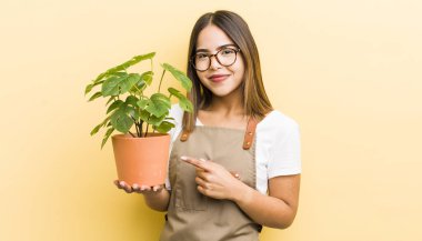 Güzel İspanyol kız neşeyle gülümsüyor, mutlu hissediyor ve bir tarafı işaret ediyor. bitki kavramı