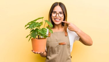 Güzel İspanyol kız kendine güvenerek kendi gülüşünü işaret ediyor. bitki kavramı