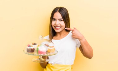 Güzel İspanyol kız kendine güvenerek kendi gülüşünü işaret ediyor. Ev yapımı kek konsepti