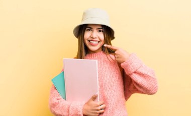 Güzel İspanyol kız kendine güvenerek kendi gülüşünü işaret ediyor. öğrenci konsepti