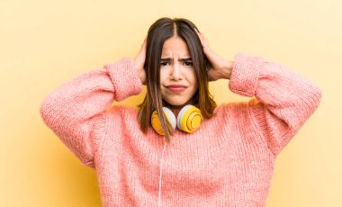 Güzel İspanyol kız stresli, endişeli ya da korkmuş, elleri başının üstünde. kulaklık konsepti