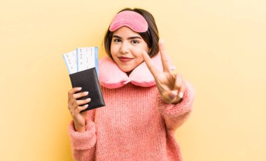 Güzel İspanyol kız gülümsüyor ve mutlu görünüyor, zafer ya da barış işareti yapıyor. uçuş yolcu kavramı