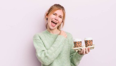 Kızıl saçlı güzel kız kendini mutlu hissediyor ve bir meydan okumayla yüzleşiyor ya da kutluyor. kahve konseptini kaldır.