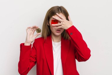 Kızıl saçlı güzel kız şok olmuş, korkmuş ya da dehşete düşmüş gibi görünüyor, yüzünü eliyle kapatıyor. Bitcoin konsepti