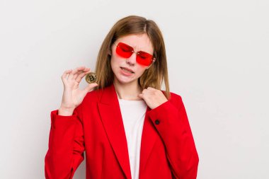 Kızıl saçlı güzel kız stresli, endişeli, yorgun ve hayal kırıklığına uğramış hissediyor. Bitcoin konsepti