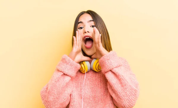 かなりヒスパニック系の女の子が幸せな気分で 手を口の横に大きな声を出す ヘッドフォンのコンセプト — ストック写真