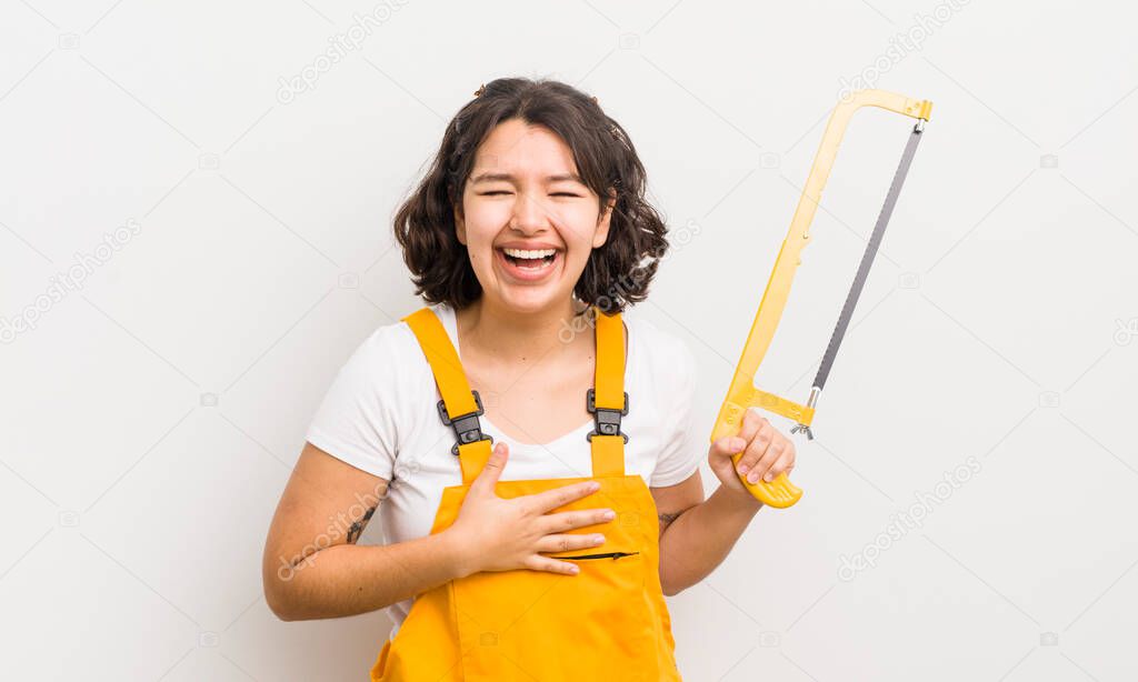 pretty hispanic girl laughing out loud at some hilarious joke. handyman and saw concept