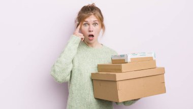 Kızıl saçlı güzel kız şaşırmış görünüyor, yeni bir düşünceyi, fikri ya da konsepti fark ediyor. nakliye kutuları kavramı