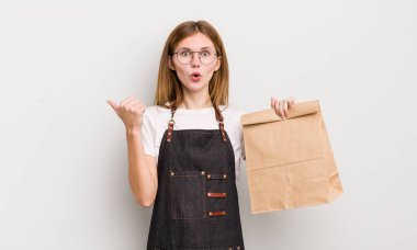 Kızıl saçlı güzel kız inançsızlıktan şaşkın şaşkın bakıyor. çalışanı götür.