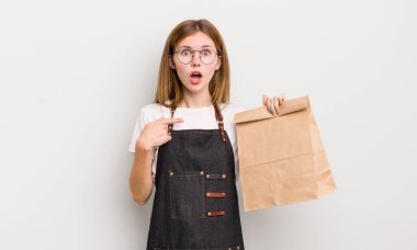 Kızıl saçlı güzel kız şaşkın ve şaşkın görünüyor. çalışanı götür.