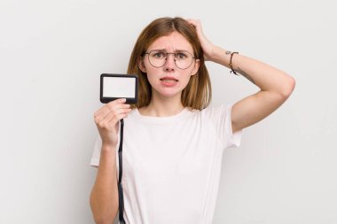 Kızıl saçlı güzel kız stresli, endişeli ya da korkmuş, elleri başının üstünde. VIP geçiş kartı konsepti