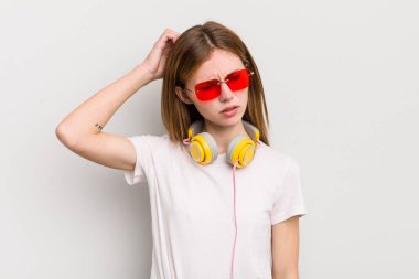 Kızıl saçlı güzel kız mutlu bir şekilde gülümsüyor ve hayal kuruyor ya da şüphe ediyor. müzik konseptini dinle