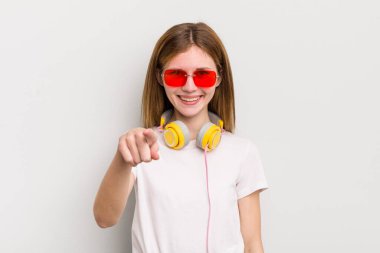Kızıl saçlı güzel kız seni seçen kamerayı işaret ediyor. müzik konseptini dinle