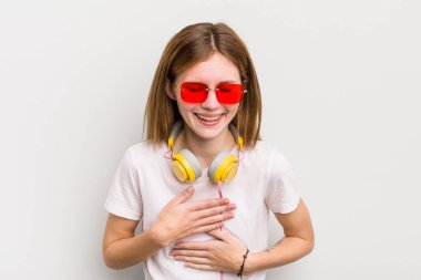 Kızıl saçlı güzel kız komik bir şakaya yüksek sesle gülüyor. müzik konseptini dinle