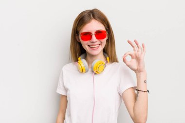 Kızıl saçlı güzel kız kendini mutlu hissediyor, iyi bir jestle onaylıyor. müzik konseptini dinle