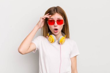 kızıl saçlı güzel kız mutlu, şaşkın ve şaşırmış görünüyor. müzik konseptini dinle