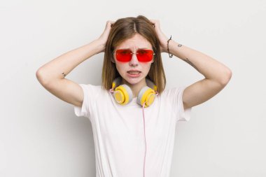 Kızıl saçlı güzel kız stresli, endişeli ya da korkmuş, elleri başının üstünde. müzik konseptini dinle