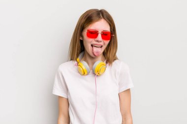 kızıl saçlı, neşeli ve asi tavırlı, şaka yapan ve dilini dışarı çıkaran güzel kız. müzik konseptini dinle
