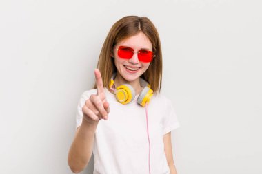 Kızıl saçlı güzel kız gururla gülümsüyor ve kendine güvenerek bir numara oluyor. müzik konseptini dinle