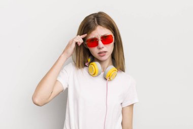 Kızıl saçlı güzel kız kafası karışık ve şaşkın hissediyor, senin deli olduğunu gösteriyor. müzik konseptini dinle